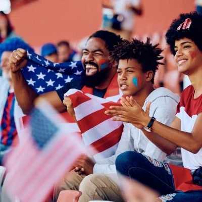 Happy black family cheering for USA during sports match at the stadium.