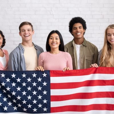 Immigration, relocation and study abroad. Cheerful young international students hold USA flag